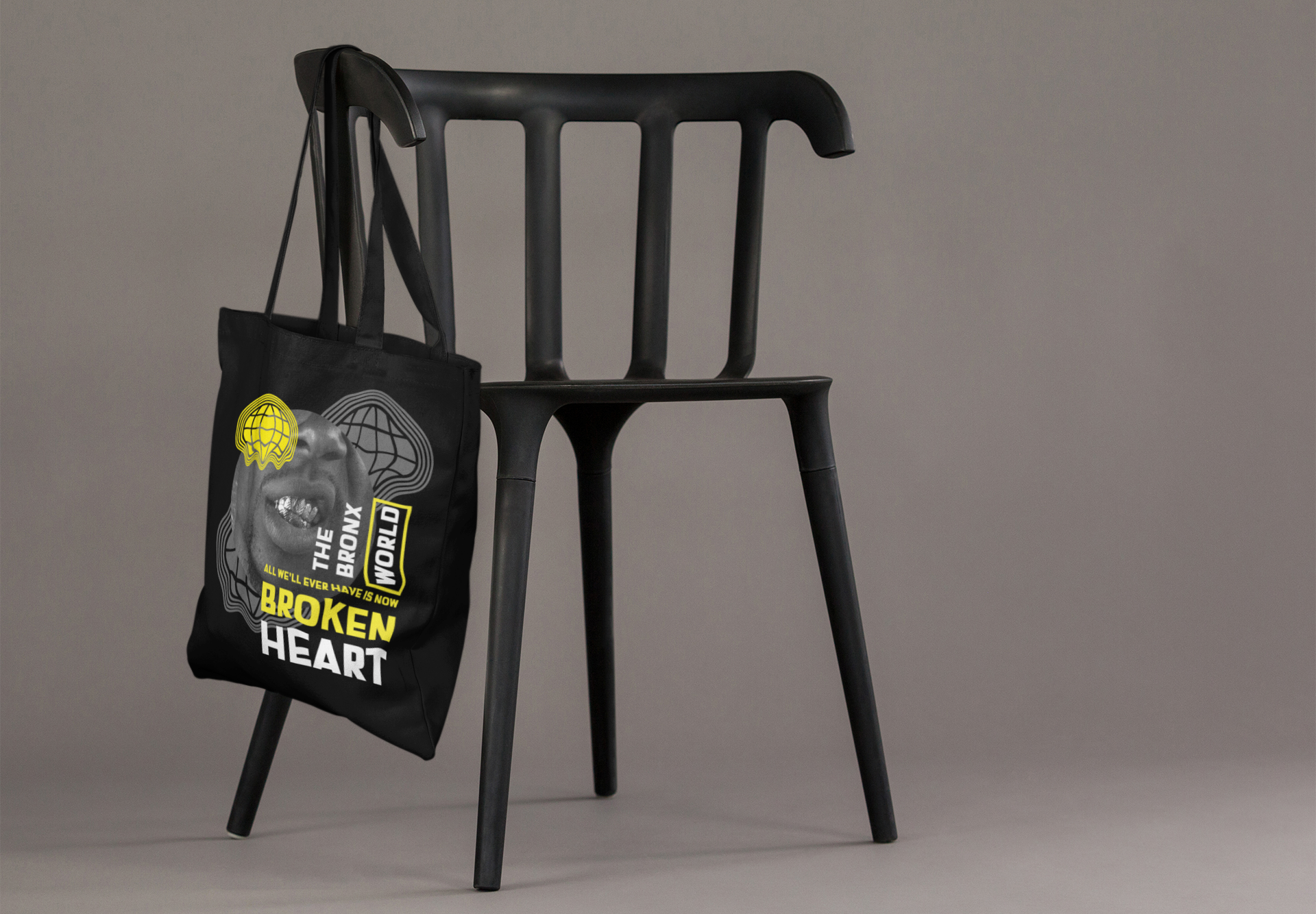 Black tote bag with graphic design hanging on a black chair against a gray background