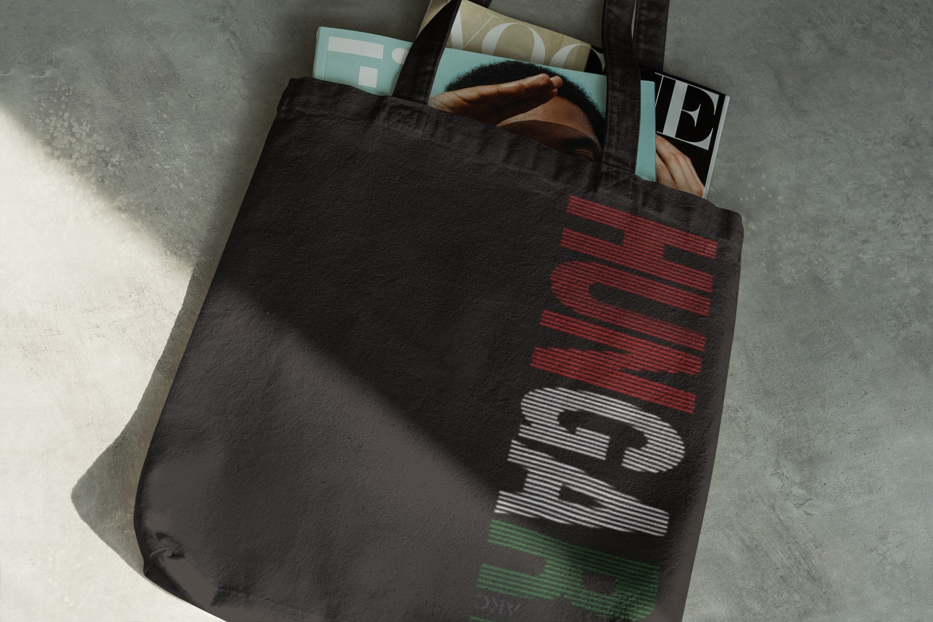 Black tote bag with 'HUNGAR' text on a concrete floor