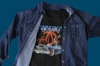 Black t-shirt with a graphic design of a classic car and palm trees, worn under a denim jacket on a blue background.