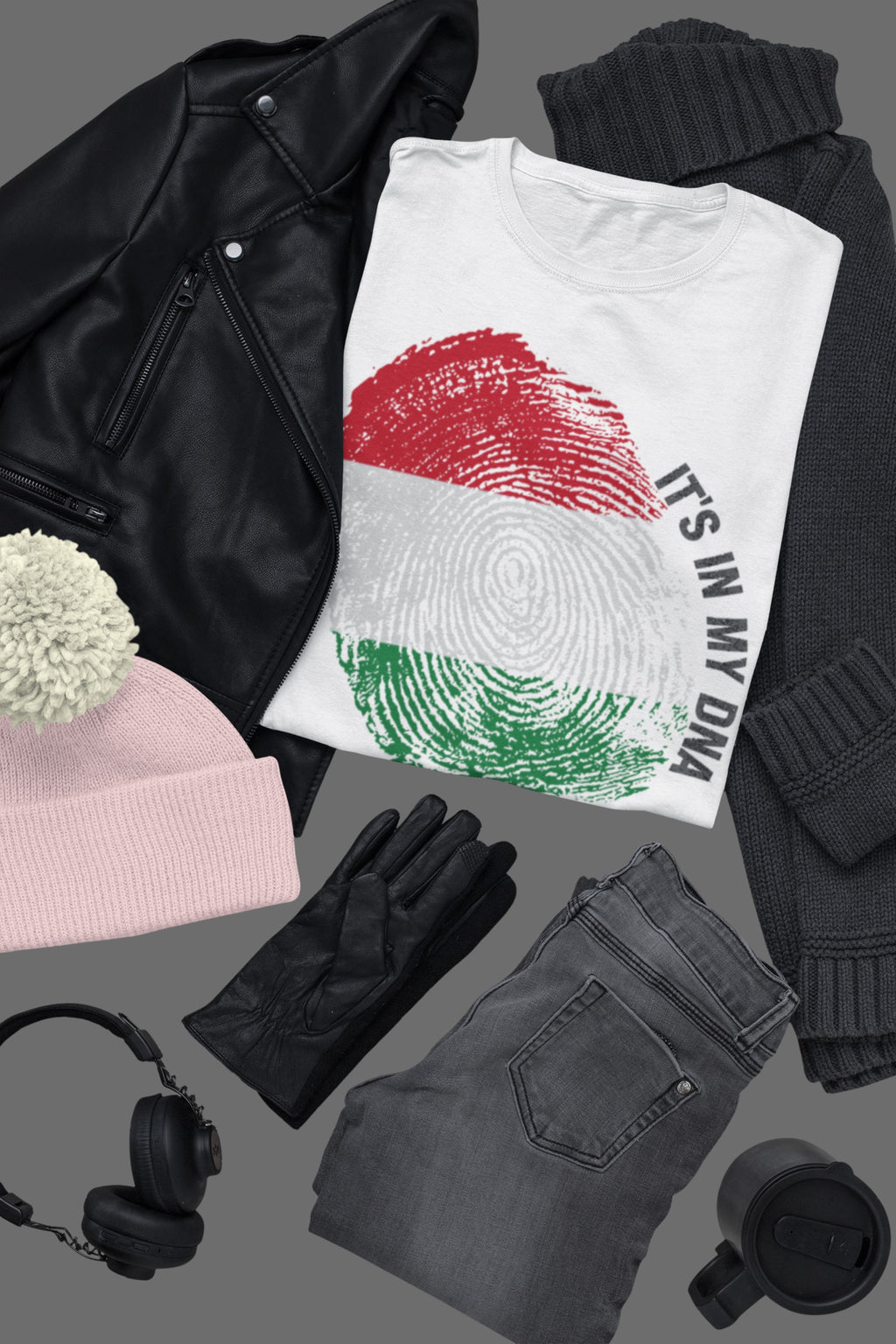 Collection of clothing and accessories including a black leather jacket, pink beanie, white t-shirt with fingerprint design, gray jeans, black gloves, and a black mug on a gray background.