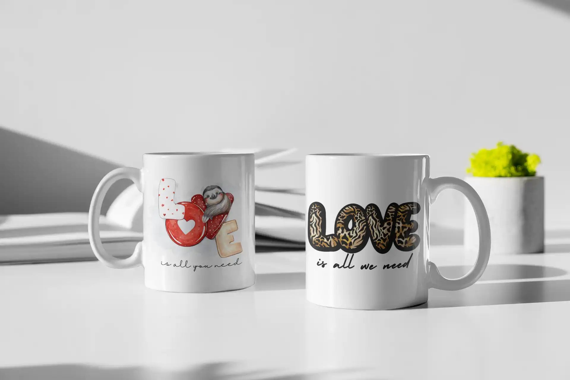 Two white ceramic mugs with romantic designs and text decorations sitting side by side.