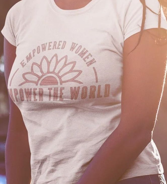Person wearing a white t-shirt with 'Empowered Women Power the World' text and sunflower graphic.