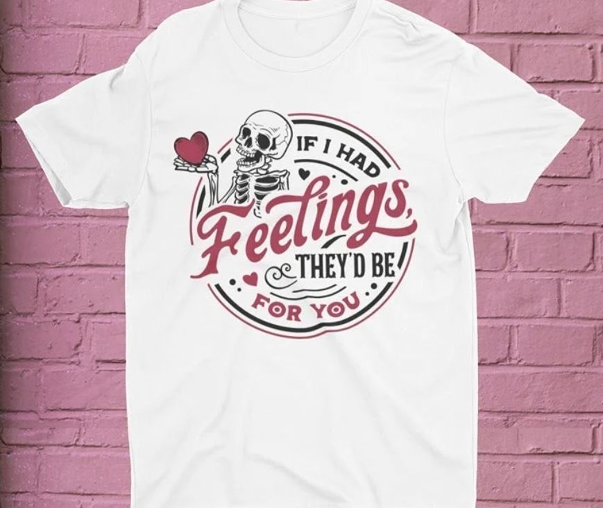 White t-shirt with skeleton graphic and text on a pink brick wall background